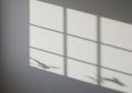 Soft shadows of window panes are cast on a smooth gray surface, forming a subtle grid Royalty Free Stock Photo