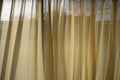 Soft sheer linen curtains billow in a gentle breeze letting daylight in through the beige material