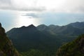 The soft silhouettes of green mountains against a blue sea in a haze and clouds