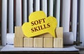 SOFT SKILLS - words on yellow paper against the background of wooden cubes and standing books