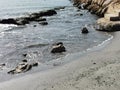 Soft small waves during calm break on granite stones of coastal zone and flow down sand of beach. Sea wave is broken against the Royalty Free Stock Photo