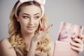 soft studio portrait of a beautiful woman with fluffy soft hoop on head doing makeup in front of a mirror in a palette, Royalty Free Stock Photo