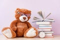 Soft stuffed toy Teddy bear with glasses, a stack of books and a stopwatch. Education concept, reading speed