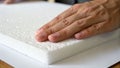 Soft styrofoam sheets being touched by hand showing texture and thickness with natural light highlighting white material surface Royalty Free Stock Photo