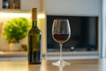 Soft sunlight illuminates a red wine glass that sits on a kitchen countertop, with a bottle in the background Royalty Free Stock Photo