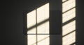 Soft sunlight streams through a window, casting a grid-like pattern of light and shadows onto a dark wall Royalty Free Stock Photo