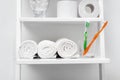 Soft towels and glass with tooth brushes on shelf near light wall in bathroom Royalty Free Stock Photo