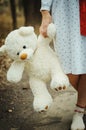 Soft toy bear on hands of girl on sleepwear outdoor.