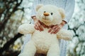 Soft toy bear on hands of girl on sleepwear outdoor.