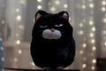 Soft toy cat with an angry expression on his face on the background of blurred garland Royalty Free Stock Photo