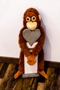 A soft toy monkey hangs on a wooden heart Portrait Royalty Free Stock Photo