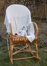 A soft toy mouse, a book and a knitted blanket on a wicker rocking chair