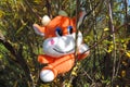 soft toy orange bull cow, symbol of 2021, attached to a tree branch, sun glare of the morning sun .