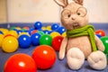 Soft toy rabbit with glasses and scarf for kids with colored balls. Bright children& x27;s toys.