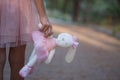 Soft toy rabbit in hands of girl walking in fall park