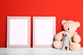Soft toys and photo frames on table  red background, space for text. Child room interior Royalty Free Stock Photo