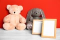 Soft toys and photo frames on table against red background. Child room interior Royalty Free Stock Photo