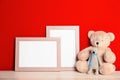 Soft toys and photo frames on table against red, space for text. Child room interior Royalty Free Stock Photo