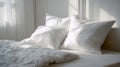 Soft white pillows and fluffy comforter illuminated by natural light in a cozy and inviting bedroom setting with calming neutral Royalty Free Stock Photo