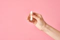 Soft white tampon in girl`s hand isolated on a pink background