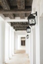 Soft white vintage castle corridor background with dark wooden beams and iron lamps in selective focus