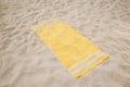 Soft yellow beach towel on sunlit sand Royalty Free Stock Photo