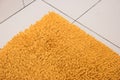 Soft yellow carpet lies on a white tile. Royalty Free Stock Photo