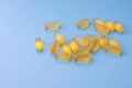 Soft yellow jelly chewable pills filled by fish oil as a source of Omega 3. Capsules are lying on blue background