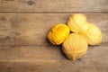 Soft yellow woolen yarns on wooden table, flat lay. Space for text