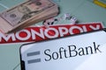 Softbank logo on smartphone placed next to Monopoly game with real money. Conceptual photo