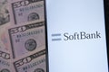 SoftBank logo on a white screen and dollar banknotes next to it. Conceptual photo for Japanese multinational conglomerate holding