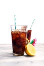 Softdrink with ice cubes, lemon and straw in glass