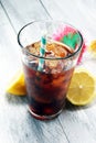 Softdrink with ice cubes, lemon and straw in glass