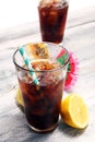 Softdrink with ice cubes, lemon and straw in glass