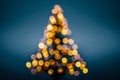 Softly glowing golden lights arranged in a triangular pattern creating a festive holiday tree effect against a deep blue blurred Royalty Free Stock Photo