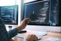 Software developer holds the pen pointing to the computer screen and is analyzing the code