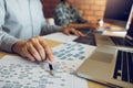 Software developer is pointing to the paper working and analyzing together the code written into the program on the computer