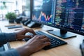 Software developer typing code on keyboard, working with stock market data on computer Royalty Free Stock Photo