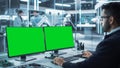 Software Developer Working on a Desktop Computer with Two Green Screen Chromakey Display Screens in Royalty Free Stock Photo