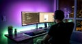 Software Developer Working on Dual Monitor Setup in Modern Home Office at Night Royalty Free Stock Photo