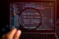 Software development and data analysis concept showing programming code on computer screen through magnifying glass, representing Royalty Free Stock Photo