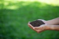 Soil in hand on green farmland background