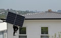 Solar construction worker on a high ladder carry a large solar panel to a house roof Royalty Free Stock Photo