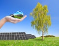 Solar energy panels on meadow and hand holding lightbulb. Royalty Free Stock Photo