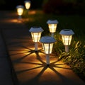 Solar garden lights with white caps illuminate a pathway, casting star-shaped patterns Royalty Free Stock Photo