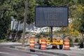 Solar mobile sign with orange cones sitting on sidewalk besides road saying Please Use Caution - Selective focus