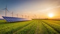 Solar panel array in a green field with wind turbines and a sunset sky Royalty Free Stock Photo