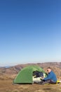 The solar panel attached to the tent. The man sitting next to mobile phone charges from the sun. Royalty Free Stock Photo