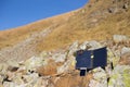 The solar panel attached to the tent. The man sitting next to mobile phone charges from the sun. Royalty Free Stock Photo