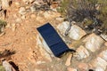 solar panel in campsite on a rock to charge phones and camera, alternative electricity source - concept of sustainable resources